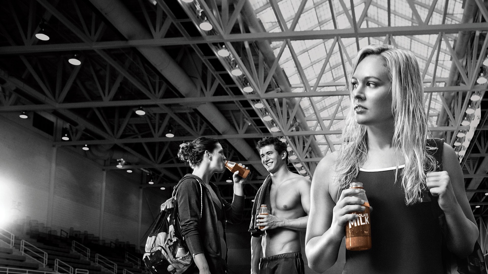 Three swimmers with bottles of chocolate milk; no wording