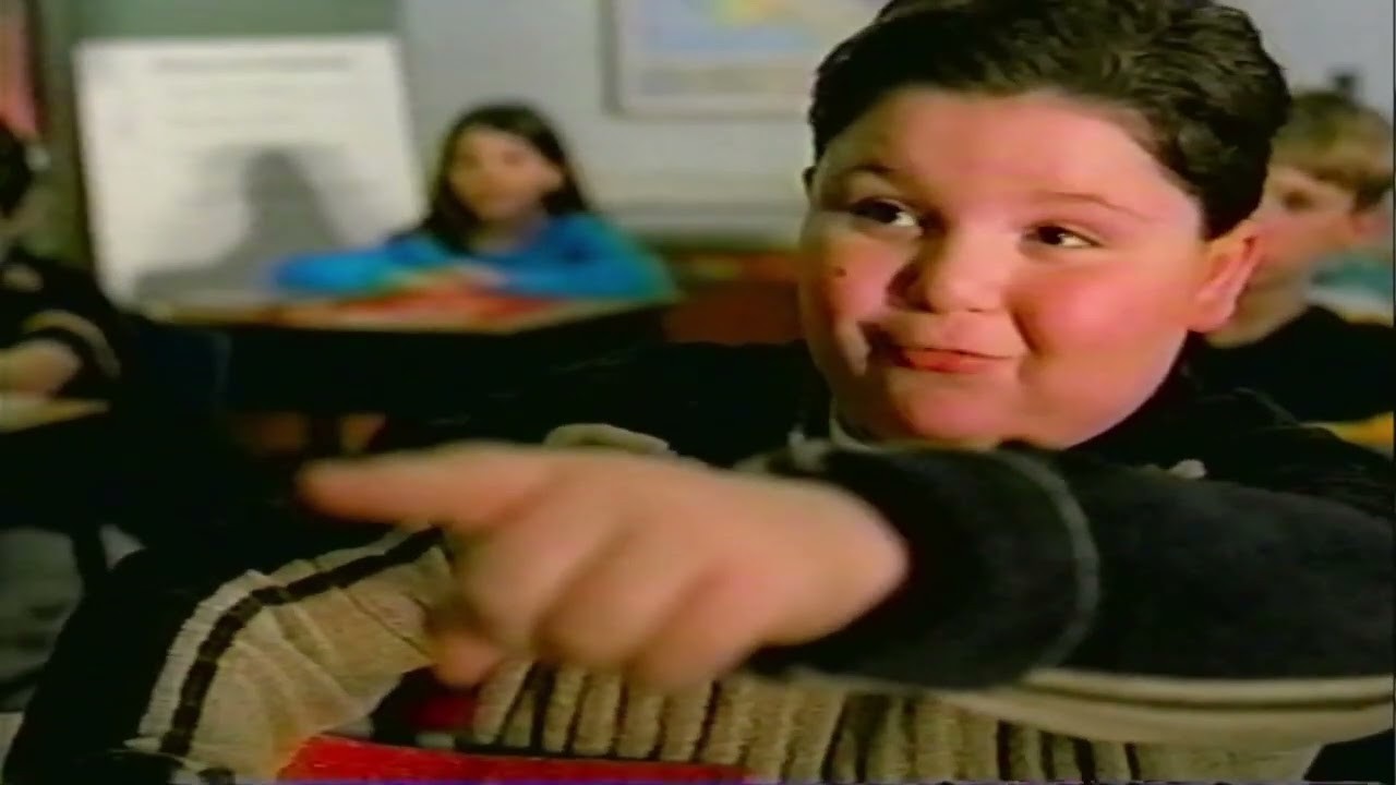 A boy at his desk points and laughs